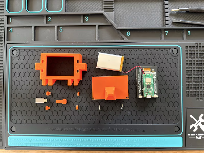 All parts laid out: Pico 2 W, Pimoroni Display Pack 2.8, LiPo SHIM, 2000 mAh battery, 3D-printed Clawd case, M3 screws